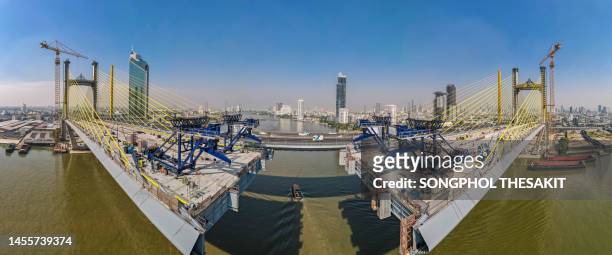 aerial view/a suspension bridge over the river is being built to connect the city. - ship's bridge imagens e fotografias de stock