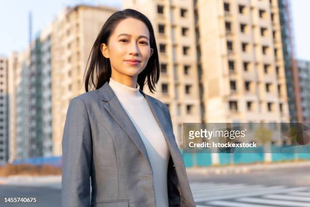 confident beautiful asian businesswoman standing in front of resident buildings - east asian ethnicity stock pictures, royalty-free photos & images