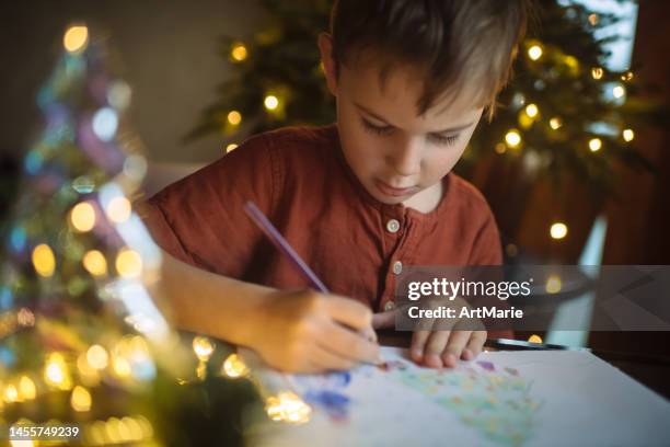 little boy drawing a picture for mom and dad for christmas - christmas cards stock pictures, royalty-free photos & images