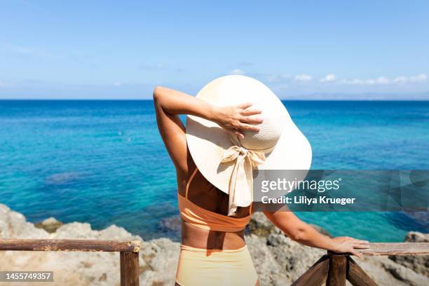 a woman looks at the sea. - sombrero mujer fotografías e imágenes de stock