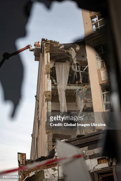 Workers clean up debris in partially damaged hotel "Alfavito" on a cherry picker truck on January 10, 2023 in Kyiv, Ukraine. The hotel was hit during...