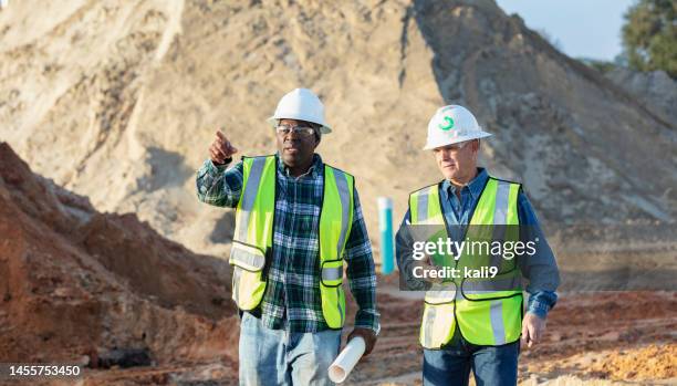 two multiracial construction workers working at job site - watching tablet outside stock pictures, royalty-free photos & images