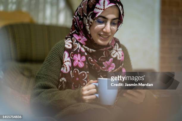 relaxed candid young woman with hot drink - hot arabic women fotografías e imágenes de stock