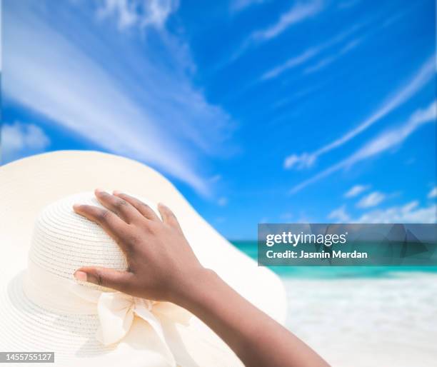 hand on hat and beautiful white sand and minty blue on the horizon - 人体部位 ストックフォトと画像