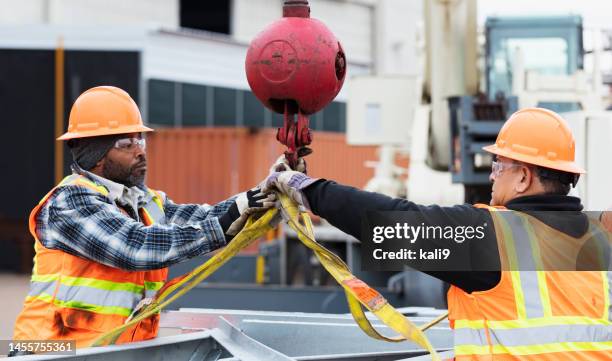 construction workers prepare object to lift with crane - hook equipment stock pictures, royalty-free photos & images