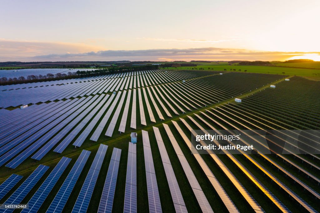 Abstract aerial/drone view over a field of solar panels at sunrise