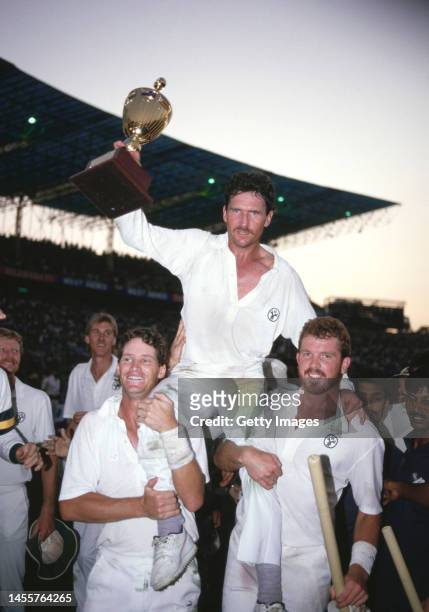 Australia Captain Allan Border holds the trophy with support from Dean Jones and Craig McDermott as Australia celebrate winning the 1987 ICC Cricket...