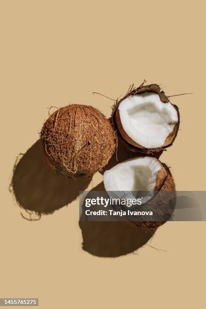 ripe coconuts on beige background. creative summer concept. half of coconut in minimal flat lay style. top view, copy space - kokosnuss stock-fotos und bilder