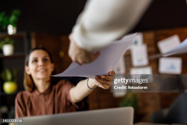 businesswoman handing her colleague a document - passes stockfoto's en -beelden