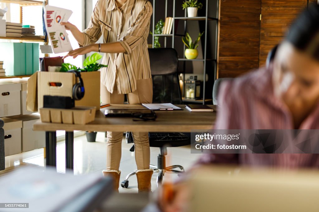 Young businesswoman packing her desk after getting fired from her job