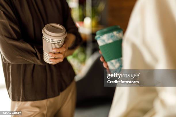 two young women standing opposite each other, chatting over cups of coffee - drinks flask stock pictures, royalty-free photos & images