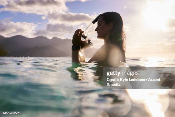 young woman prepares to put on snorkel and mask - tahiti stock pictures, royalty-free photos & images
