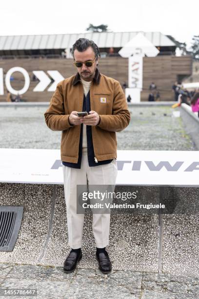 Guest wearing a Carhartt jacket with fur collar and white pants at Fortezza Da Basso on January 11, 2023 in Florence, Italy.
