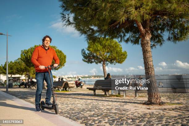 man riding a scooter along the edge of setúbal beach - setúbal district stock pictures, royalty-free photos & images