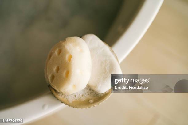 a bar of soapy soap and a loofah washcloth lying on the edge of the tub in the bathroom - barbade stock-fotos und bilder