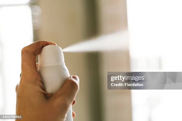 a bottle of white deodorant spray spraying a jet of air in a woman's hand - hairspray stock-fotos und bilder