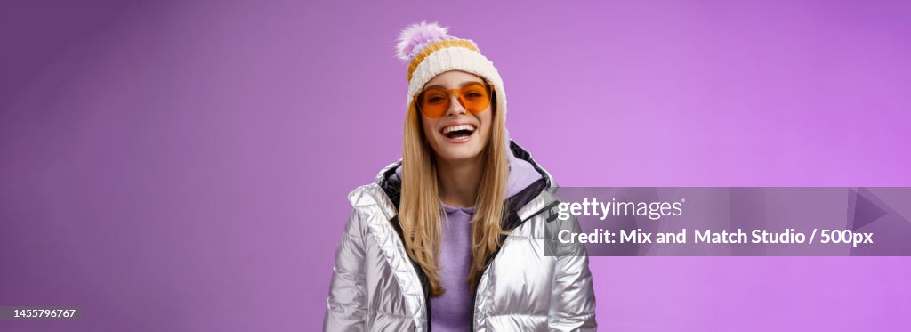Stylish friendly charismatic blond woman in silver shiny jacket hat