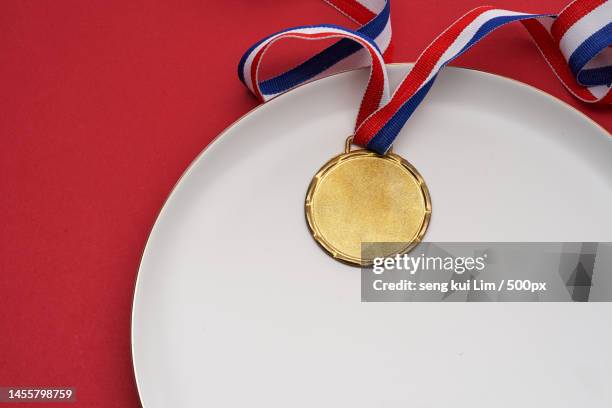 gold medal on the dinner plate against red background,malaysia - prima esperienza foto e immagini stock