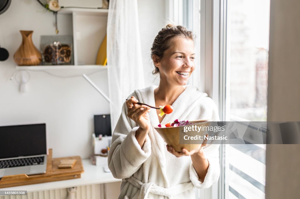 Beautiful woman eating healthy vegetable salad wearing bathrobe
