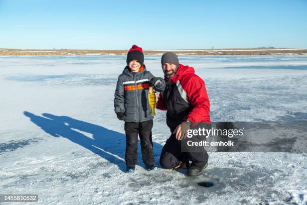 father & son holding up fish caught ice fishing - ice fishing stock pictures, royalty-free photos & images