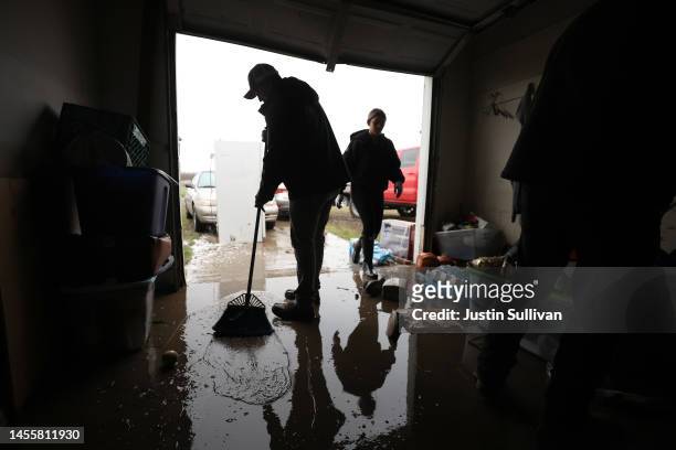 Randy Diaz sweeps water out of the garage of his father's flooded home on January 11, 2023 in Planada, California. The Central Valley town of Planada...