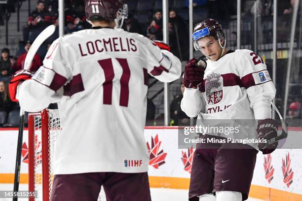 Anri Ravinskis of Team Latvia celebrates a goal by teammate Dans Locmelis during the second period against Team Austria in the relegation round of...