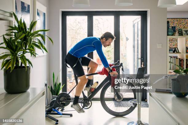 man working out on his indoors cycling turbo trainer - exercise bike fotografías e imágenes de stock