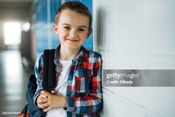 schoolboy standing in front of lockers in school corridor - only boys stock pictures, royalty-free photos & images