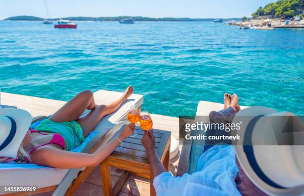 couple relaxing and toasting with a spritz cocktail on a beach deck over the ocean - croatia coast imagens e fotografias de stock