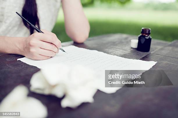 womans hand writing love letter with ink outdoor - love letter stock-fotos und bilder