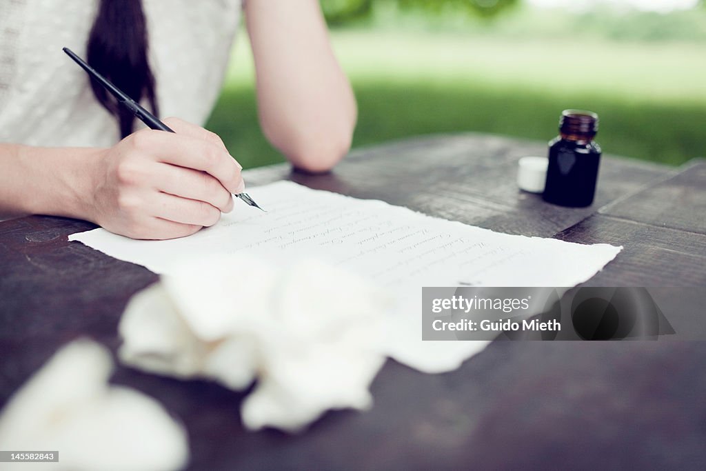 Womans hand writing love letter with ink outdoor