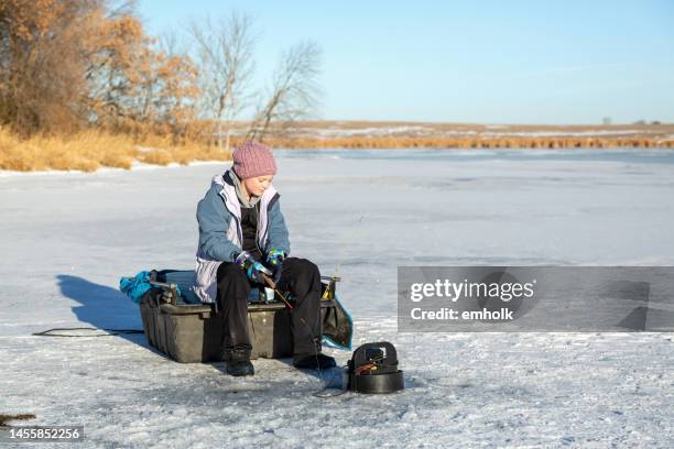 girl ice fishing on frozen lake in winter - ice-fishing stock pictures, royalty-free photos & images