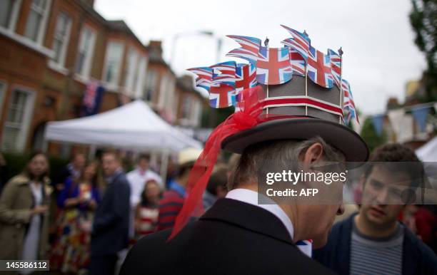 Man wears a hat on which he sticked British flags during a street party organised by residents of Battersea in south London on June 2 as Britain...