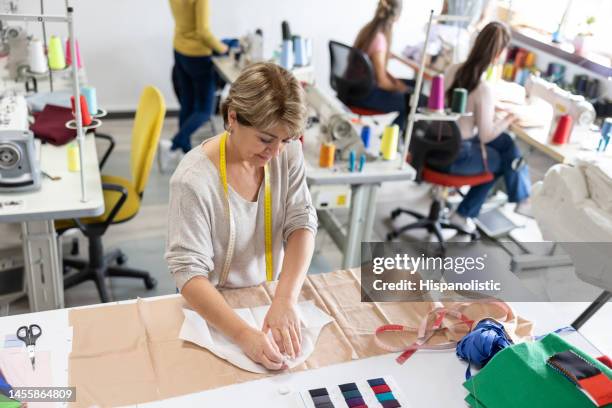 seamstress drawing a patter on fabric while working at an atelier - garment factory stock pictures, royalty-free photos & images