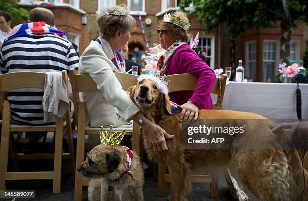 Two women caress two dogs wearing crowns as residents of a street in Battersea hold a Jubilee street party in London, on June 2 as Britain celebrates...