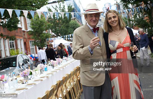 Couple poses with glasses of wine as residents of a street in Battersea hold a Jubilee street party in London, on June 2 as Britain celebrates Queen...