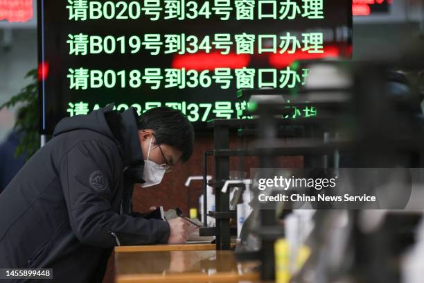 Man fills out application form at the Exit and Entry Service Center on January 11, 2023 in Beijing, China. People flocked to local exit and entry...