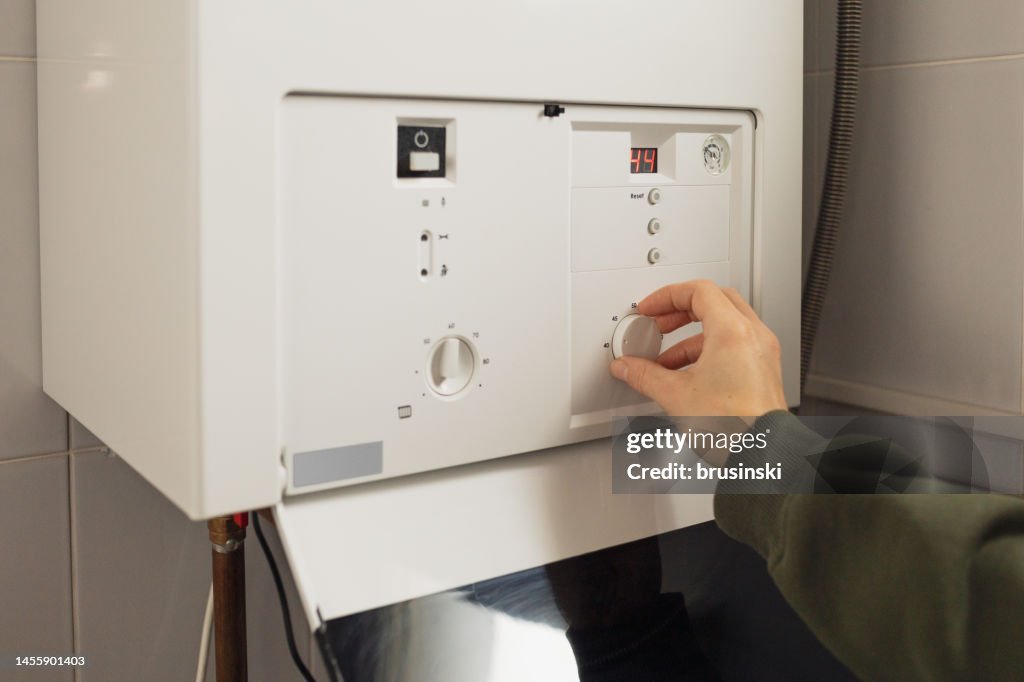 A woman reduces the power of the gas boiler in her home due to an energy crisis