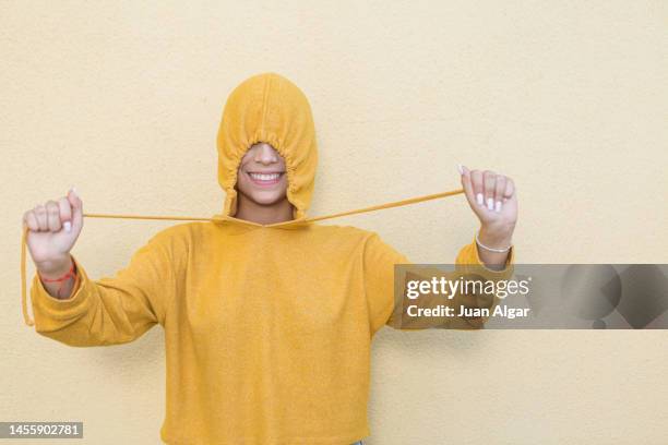 anonymous cheerful teenager in yellow hoodie - beige background stock pictures, royalty-free photos & images