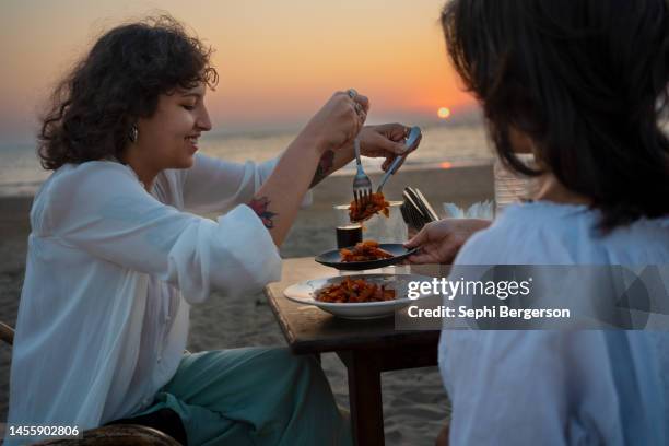 zwangloses essen am strand in der abenddämmerung - goa beach stock-fotos und bilder