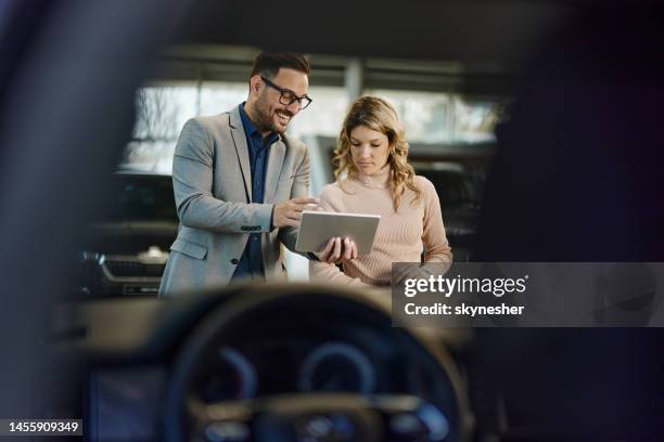 glücklicher verkäufer und sein kunde mit touchpad in einem showroom. - car salesman stock-fotos und bilder