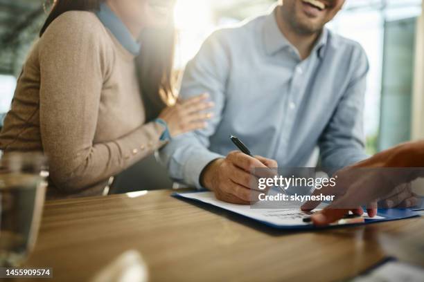 close up of unrecognizable couple signing a contract in the office. - mortgage stock pictures, royalty-free photos & images