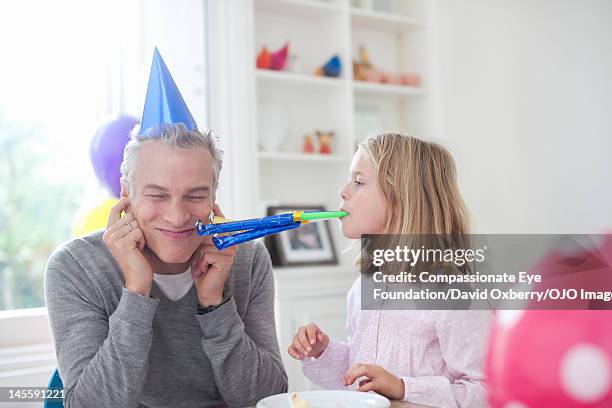 girl (7-8) blowing party horn blower at father - party horn blower bildbanksfoton och bilder