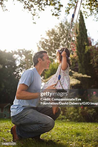 father pushing daughter (3-4) on swing - children swinging stock pictures, royalty-free photos & images