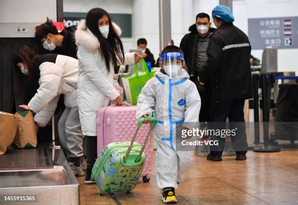 Child wearing personal protective equipment walks with a suitcase at Beijing South Railway Station during the 2023 Spring Festival travel rush on...