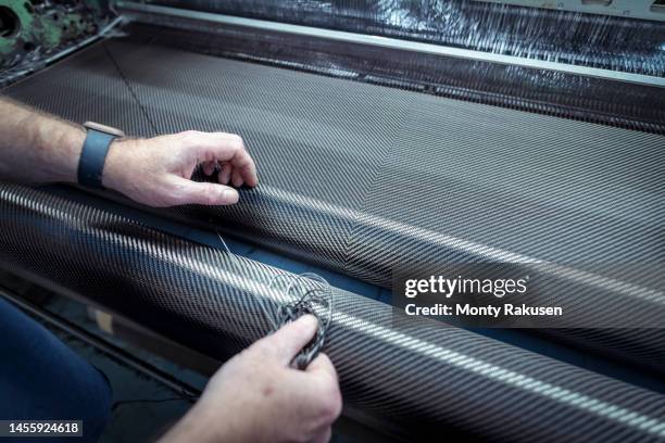 close-up of operators hands weaving carbon fibre in mill for automotive use - carbon fiber manufacturing stock pictures, royalty-free photos & images