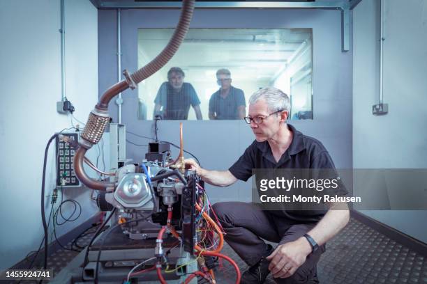 operator adjusting hydrogen engine in test bay in automotive research facility - group h photos et images de collection