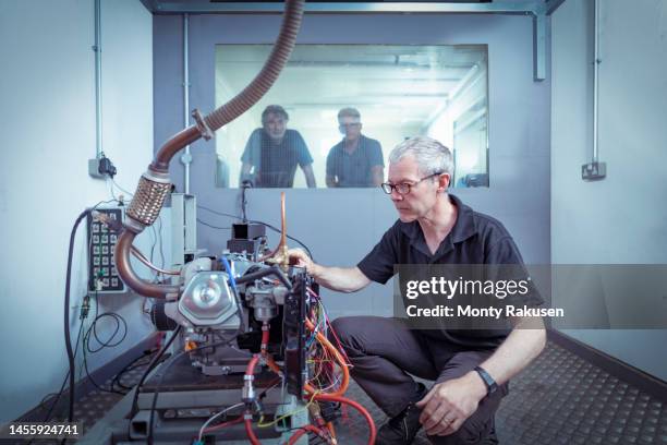 operator adjusting hydrogen engine in test bay in automotive research facility - group h foto e immagini stock