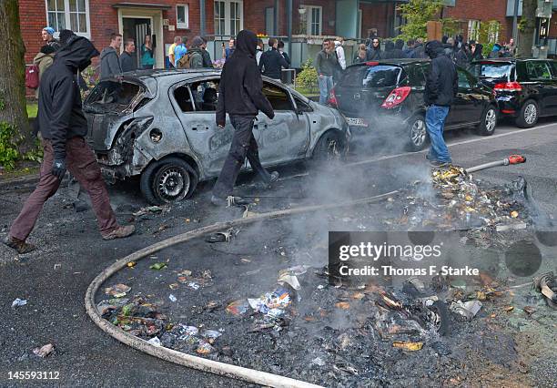 Leftist protesters walk past a burned out car during a march by neo-Nazis on June 2, 2012 in Hamburg, Germany. Thousands of protesters took to the...