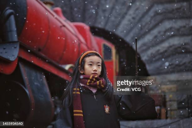 Girl poses with a wand at the Wizarding World of Harry Potter of Universal Beijing Resort as the first snow of the season descends upon the city on...